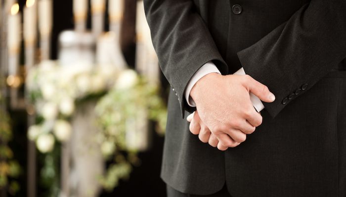 Hand holding his hands at a funeral